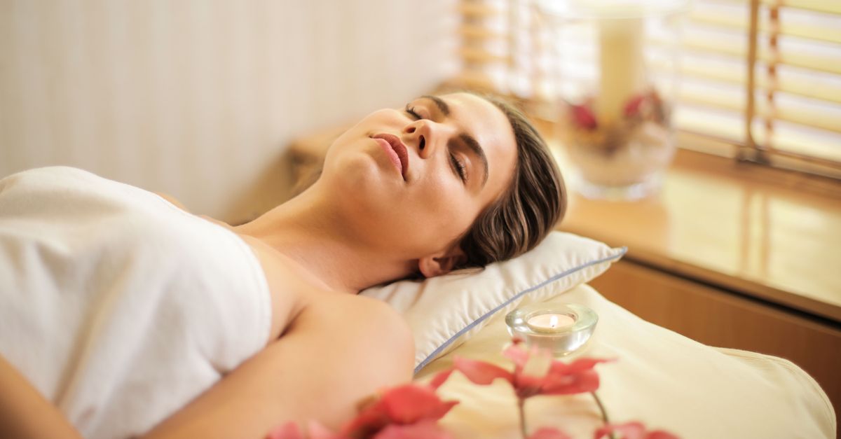 Woman enjoying a relaxing spa day with flowers and candles indoors.